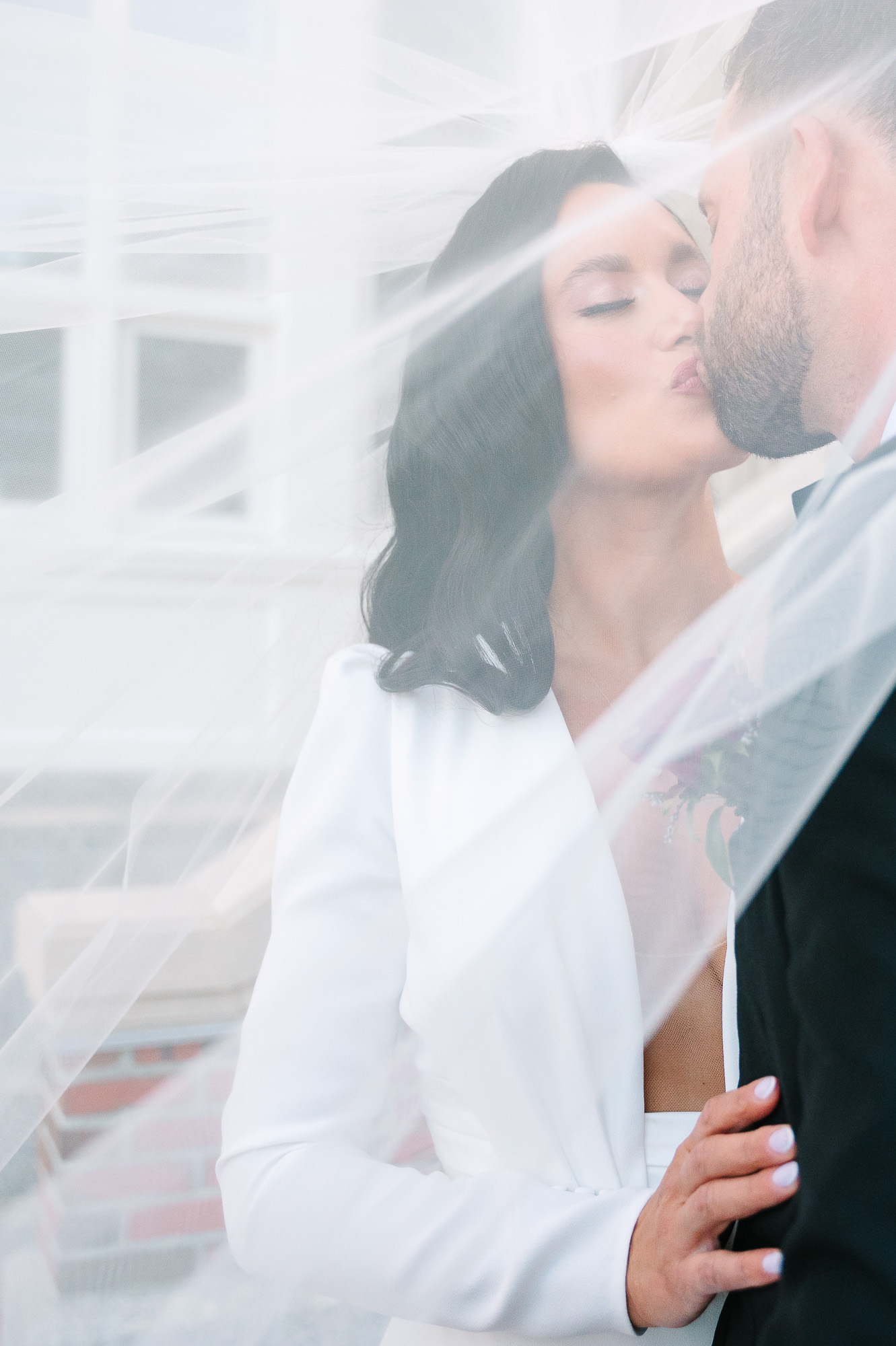 bride and groom kissing by the waterfront at the boston harbor hotel