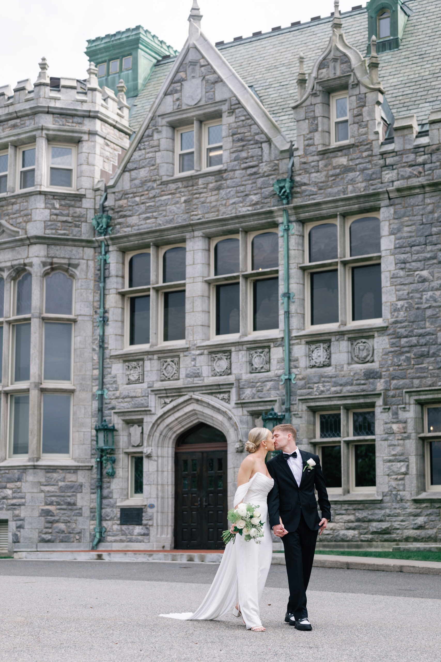 bride and groom walking and kissing on wedding day in front of castle wedding venue