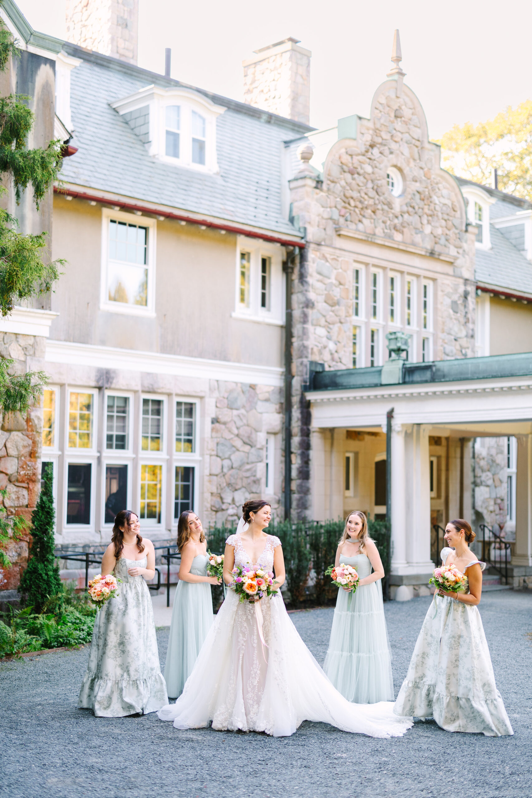 Bridesmaids in green dresses with colorful bouquets at Blithewold Manor in Rhode Island.